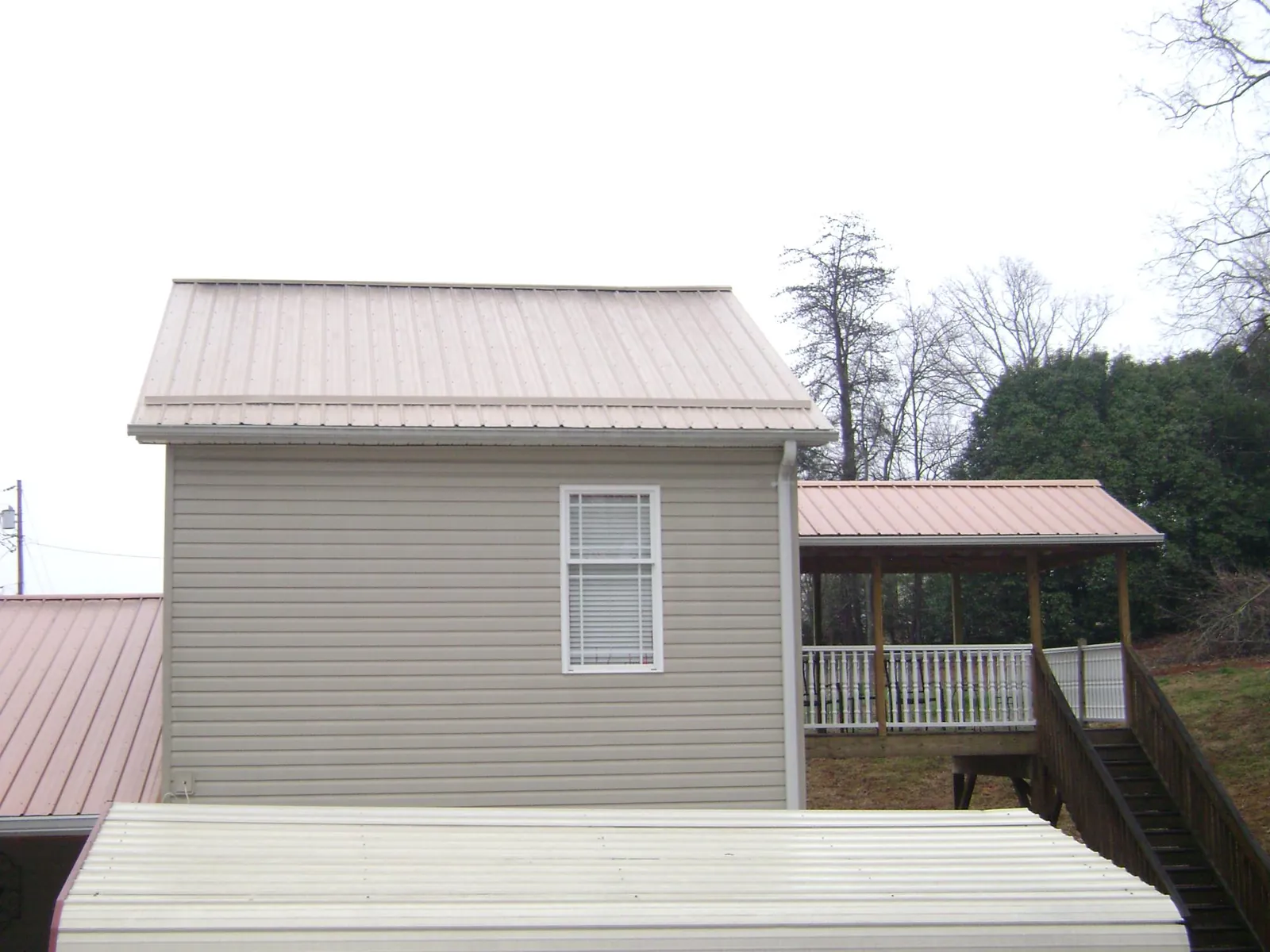 Tan metal roofs on a two story addition and attached porch, from a Roof Replacement job in Bridgewater